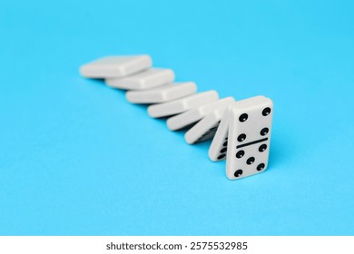 Domino effect. Tiles falling on light blue background