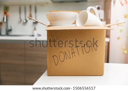donate household items - box with tableware for donation on kitchen table