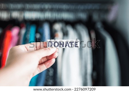 Donate sign held in front of wardrobe full of clothes, concept of excessive shopping and consumerism Foto d'archivio © 