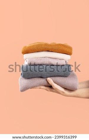 Donating old warm clothes, second hand, economic crisis, fighting the cold, warm clothes, saving money, compassion, connection, peach background. Vertical orientation.