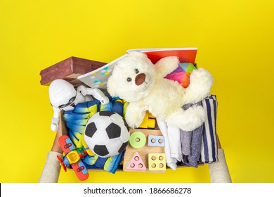 Donation Box With Baby Kid Toys, Books, School Supplies, Clothing For Charity On Yellow Background. Top View