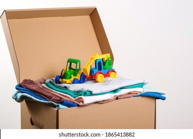Donation box with children's things and toys. Donation box full with stuff for donate. Help poor. Case full of clothing for poor families. Sharity social activity. Cardboard box with clothes.