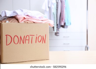 Donation Box With Clothes On Table In The Room