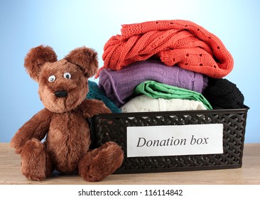 Donation Box With Clothing On Blue Background Close-up