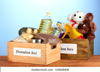 Donation box with food and children's toys on blue background close-up