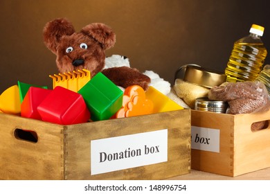 Donation box with food and children's toys on brown background close-up