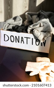 Donation Box With Old Used Clothes Indoors. Happy Charity. Winter Clothes In A Cardboard Box. Clothing Donation Or Recycling Seasonal Clothing