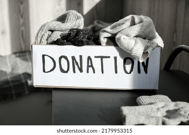 Donation Box With Old Used Clothes Indoors. Happy Charity. Winter Clothes In A Cardboard Box. Clothing Donation Or Recycling Seasonal Clothing