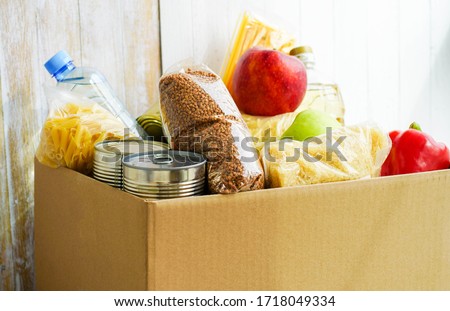Donation box with various food. Open cardboard box with butter, canned goods, cereals and fruits.