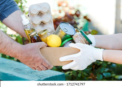 Donation box with various food. A volunteer passes a cardboard box with dry cereals, canned goods, eggs, oil. From hand to hand. Help during a pandemic. Food donations or food delivery concept.