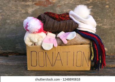     Donation Box With Warm Winter Clothes On Old Wooden Background. 