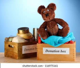 Donation boxes with clothing and food on blue background close-up