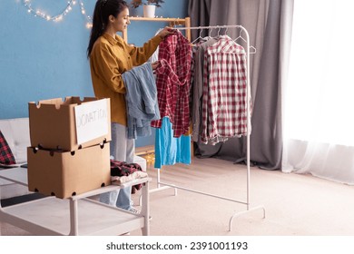 Donation and charity concept. Woman putting clothes in donation boxes preparing humanitarian aid for the poor. Copy space - Powered by Shutterstock