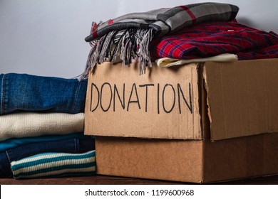 Donation Concept. Donation Box With Donation Clothes On A Table. Charity. Helping Poor And Needy People