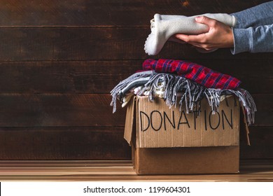 Donation concept. Donation box with donation clothes on a wooden background. Charity. Helping poor and needy people. Copy space  - Shutterstock ID 1199604301