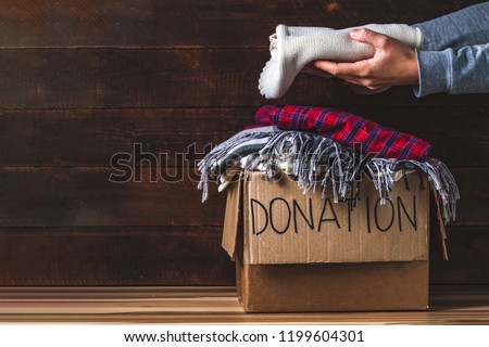 Donation concept. Donation box with donation clothes on a wooden background. Charity. Helping poor and needy people. Copy space 