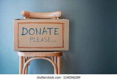 Donation Concept. Empty Donate Box on Chair against Wall in Public Space - Powered by Shutterstock