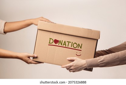 Donation Concept. The Volunteer Giving a Donate Box to the Recipient. Standing against the Walll