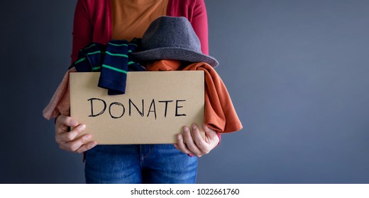 Концепция пожертвования. Женщина держит Коробка пожертвования с полным одежды