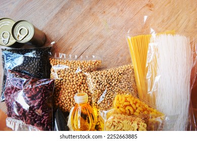 Donations food with canned food on wooden table background. pasta canned goods and dry food non perishable with pea beans cooking oil instant noodles macaroni , donate concept - Shutterstock ID 2252663885