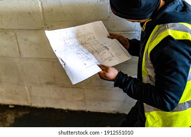 Doncaster, UK, CIRCA-DECEMBER-2020 Workers Reading Site Plans Site Manager Looking At Blueprints Wearing Hi Viz Vest