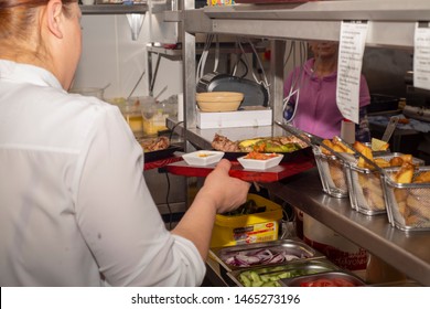 Doncaster, UK - May 11 2019: A Waitress Grabs Two Plates From The Kitchen During A Busy Saturday Night Dinner Service On 11 May At La Boca Argentine Steak House Restaurant, 1 Netherhall Road