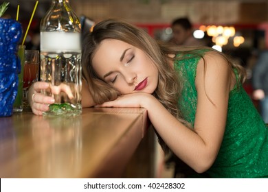  Done. Horizontal portrait of a young seductive woman sleeping drunk on the bar table after a lot of drinks.