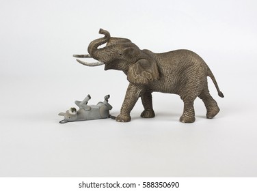 A donkey lays on its back blocking a walking elephant. The donkey and elephant are symbols for political parties.