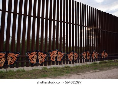 Donna, Texas USA- December 19, 2016: Editorial. The US/Mexico Border Fence At Donna Texas And Rio Bravo Mexico. Fence Has Butterflies And A Peace Sign Attached To It As A Protest Against Trump.