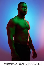 Dont Act Like Youre Not Impressed. Studio Shot Of A Man Posing Shirtless Against A Neon Background.