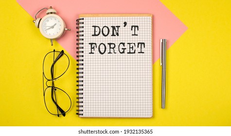 Don't Forget Notice on the notepad with pen, glasses and alarm clock