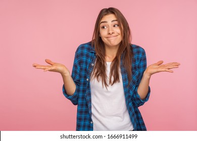 Don't know answer! Portrait of funny confused girl in checkered shirt shrugging shoulders with clueless embarrassed expression, having doubts, not sure. indoor studio shot isolated on pink background