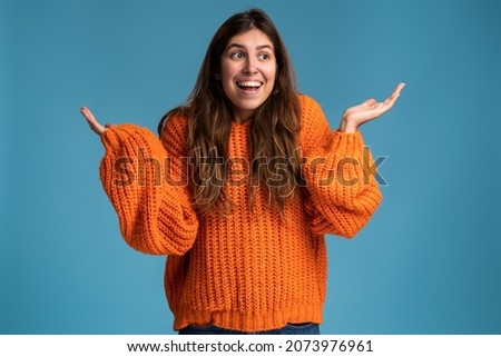 Don't know answer. Portrait of funny confused girl shrugging shoulders with clueless embarrassed expression, having doubts, not sure. Indoor studio shot isolated on blue background 