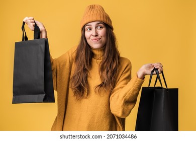 Don't know. Confused clueless woman, fashion stylist gesturing doubt, not sure which clothes to choose, standing with trendy shopping bags. Indoor studio shot 