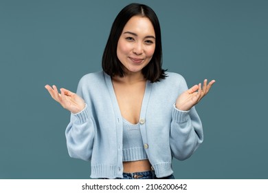 I Don't Know. Portrait Of Confused Beautiful Brunette Young Woman In Casual Style Standing With Raised Arms And Looking At Camera. Indoor Studio Shot Isolated On Blue Background 