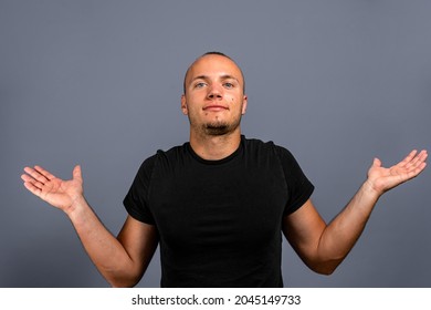 I Don't Know. Portrait Of Confused Handsome Young Man In Blue Casual Style Black Shirt Looking At Camera With Answer. Indoor Studio Shot, Isolated On Gray Background.