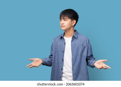 I don't know, Puzzled and clueless young handsome Asian man with arms out, Standing on blue background