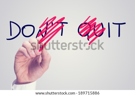 Don't Quit - Do It, conceptual image with a man scrubbing through letters in the words Don't Quit converting them to Do It with a red pen in a motivational message of hope and perseverance.