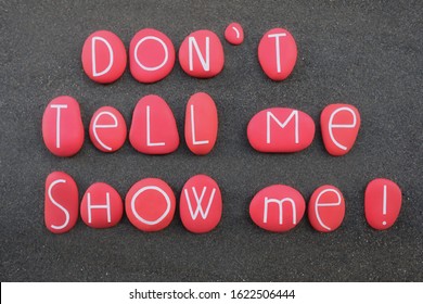 Don't Tell Me, Show Me. Motivational Phrase Composed With Red Colored And Carved Stone Letters Over Black Volcanic Sand