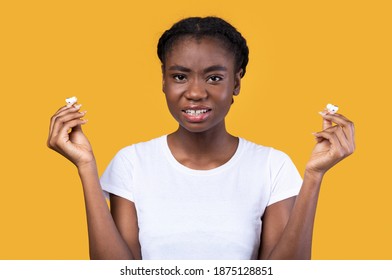 I Don't Want To Hear It. Displeased Black Woman Holding Earbuds Earphones Looking At Camera Not Liking Music Standing In Studio Over Yellow Background. Auwful Playlist Concept