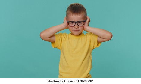 Dont Want To Hear And Listen. Frustrated Annoyed Irritated Toddler Children Boy Covering Ears And Gesturing No, Avoiding Advice Ignoring Unpleasant Noise Loud Voices. Young Kid On Blue Wall Background