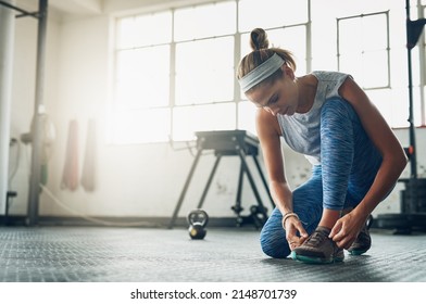 I dont want my shoes falling off during a workout. Shot of a young attractive woman tying her shoelaces in a gym.