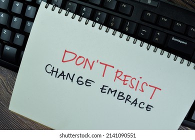 Dont't Resist Change Embrace write on a book isolated on Wooden Table. Selective focus on don't resist change embrace text