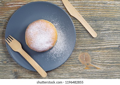 Donut Berliner With Jam And Powdered Sugar In A Plate With A Wooden Fork And Knife On An Old Table, Top View