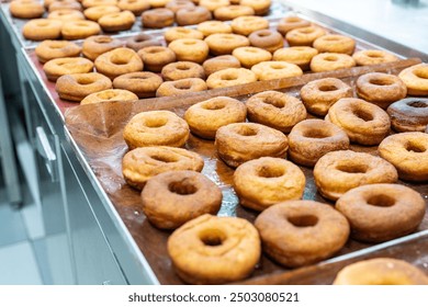 Donut production. The donuts are fried, glazed, and laid out on racks at a donut bakery. High quality photo - Powered by Shutterstock