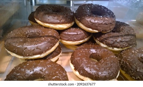 Donuts With Black Chocolate Glaze Supermarket Shelves For Sale. Sweet Doughnut. Unhealthy Food With Sugar. Bakery Homemade Product Made From Scratch. Close-up Cake. Fashionable Food Trends. Freshness.