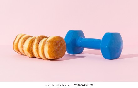 Donuts And Blue Dumbell On Pastel Background.  Calories Need Workout Concept.