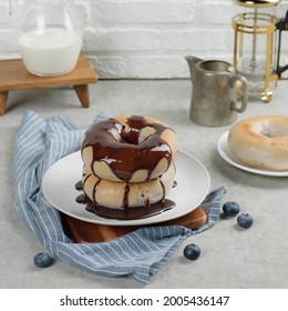 Donuts with chocolate topping on table with milk jar