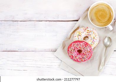 Donuts And Coffee On A White Wood Background. Toning. Selective Focus On Red Donut