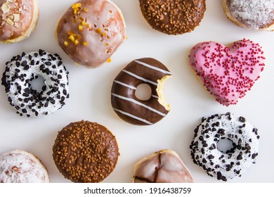 Donuts with colorful icing on a white background. Bitten donut in the middle. The concept of dependence on sweet. Love of sweet. The concept of junk food. Background for design.